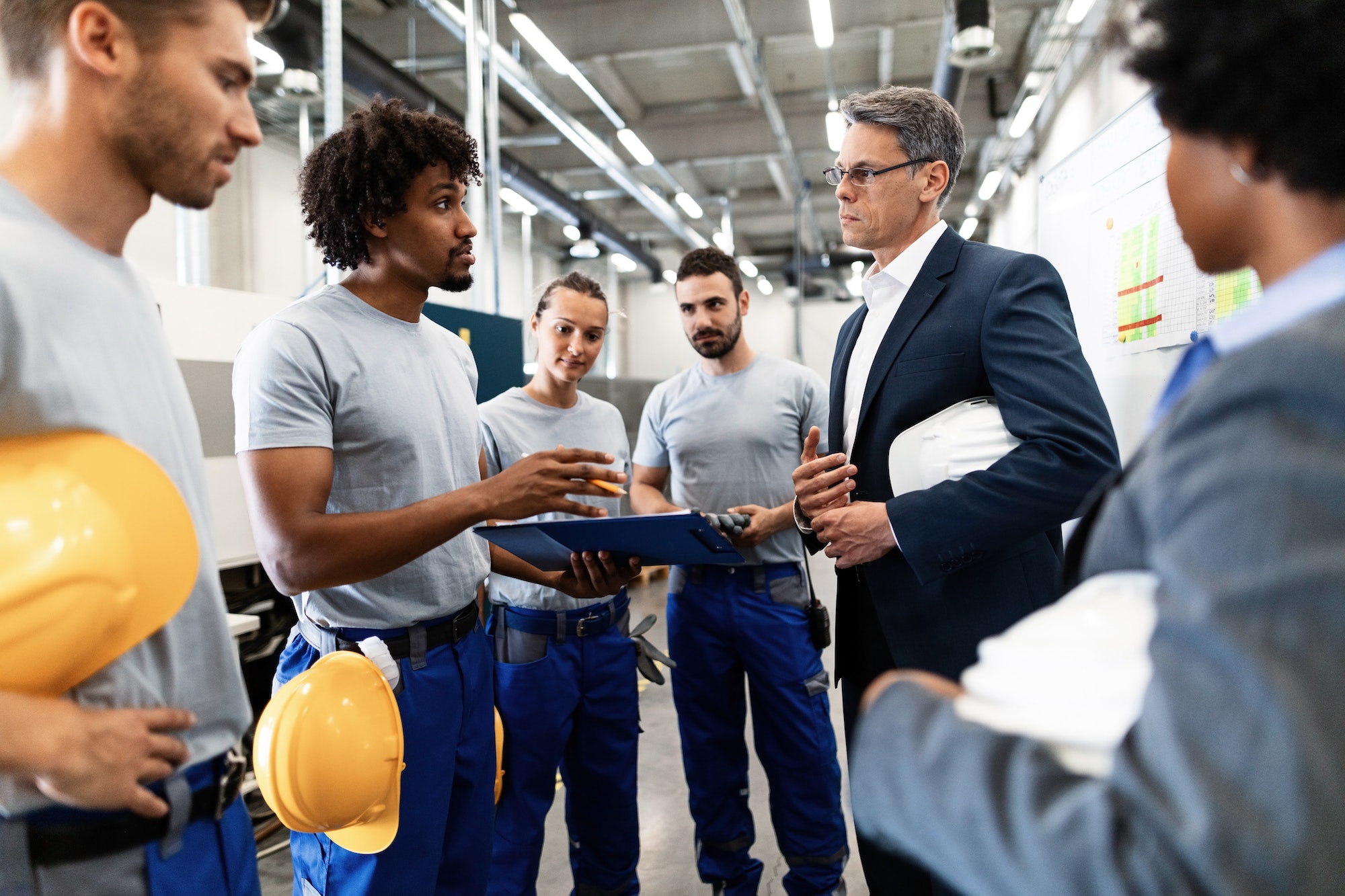 African American worker and businessman talking about reports while having staff meeting in factory.